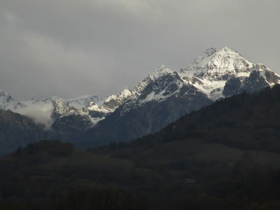 A snow-covered peak of the Belledonne range above Grenoble under a grey sky