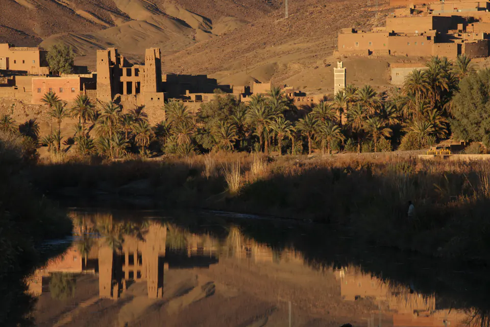 A kasbah and its palm grove reflected in the Draa river at Agdz