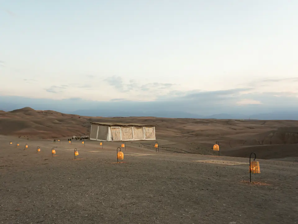 A tent lit by candles at dusk in the Agafay desert
