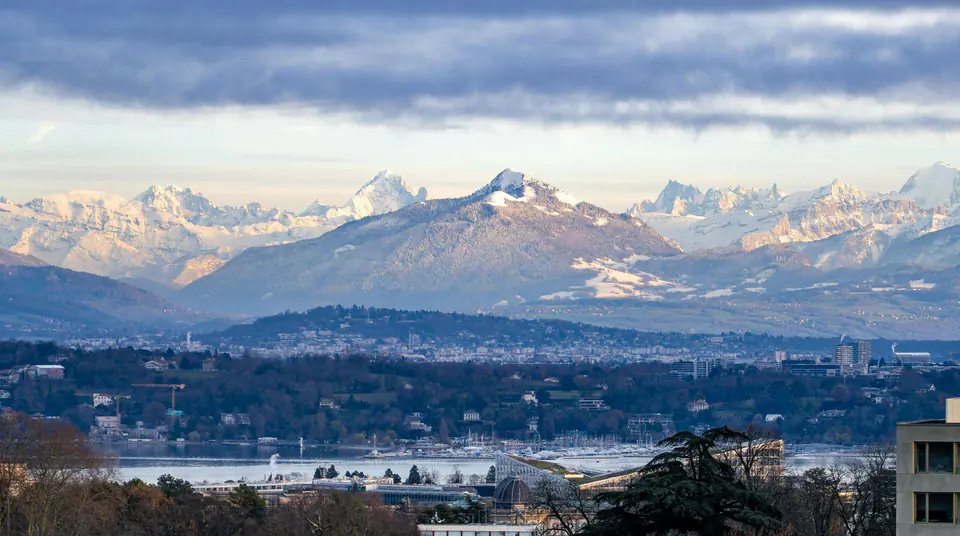 Snow-capped Alps above the rooftops of Geneva and a strip of the lake