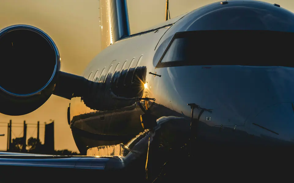 The nose and engine of a dark private jet catching golden evening light