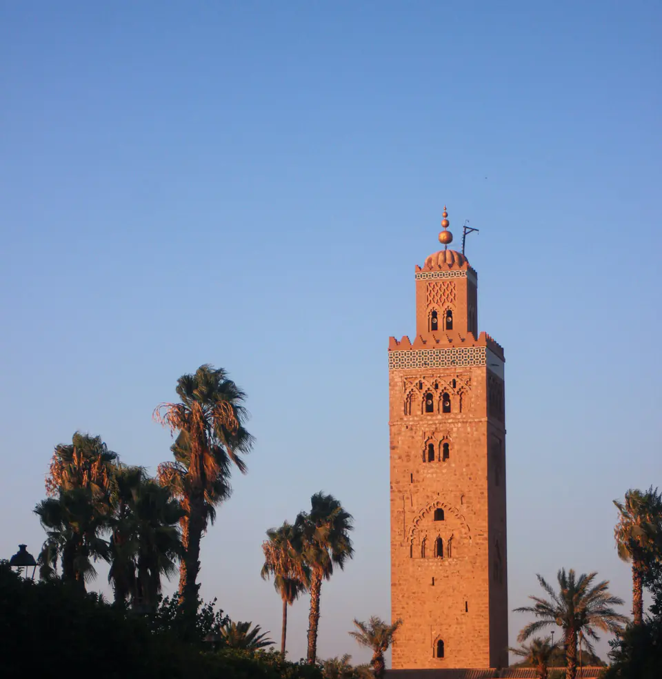 The Koutoubia minaret in Marrakech at blue hour, framed by palms