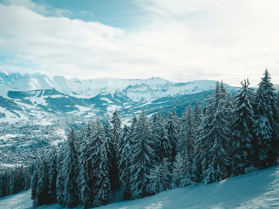 Megève in its snowy valley, seen through snow-laden fir trees