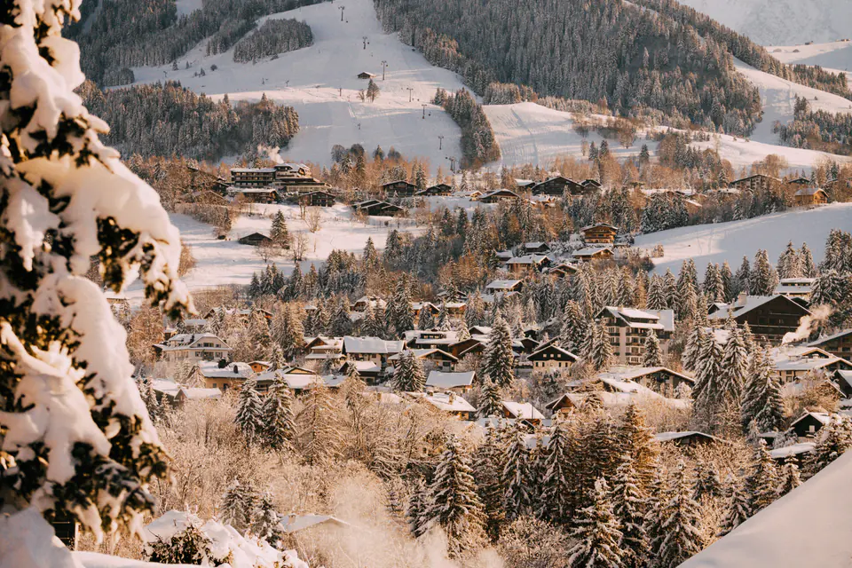 Chalets and snowy larches in Megève in low winter sun