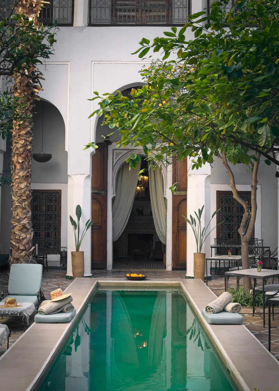 A courtyard pool framed by white arches in a Marrakech riad