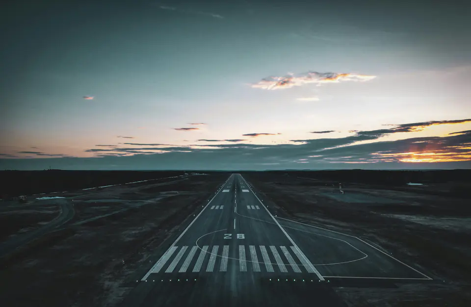 A runway seen from above at dusk, its lights leading to the horizon