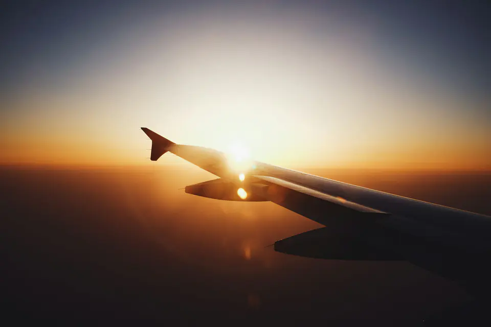 An aircraft wing in silhouette against a low sun