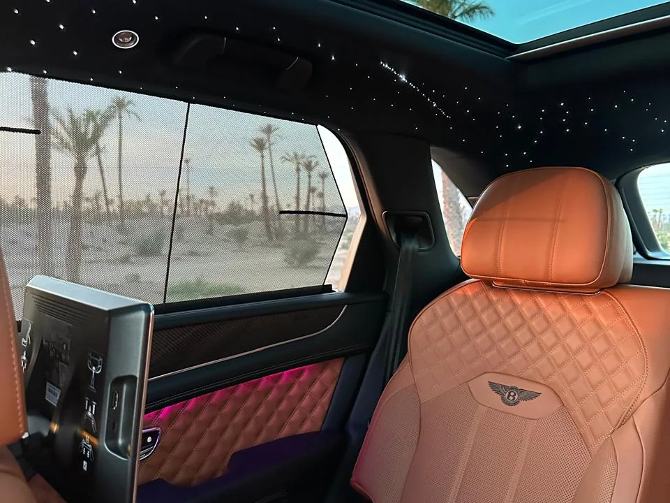 The rear seat of an Accrocar Bentley Bentayga under a starlight roof, palms outside