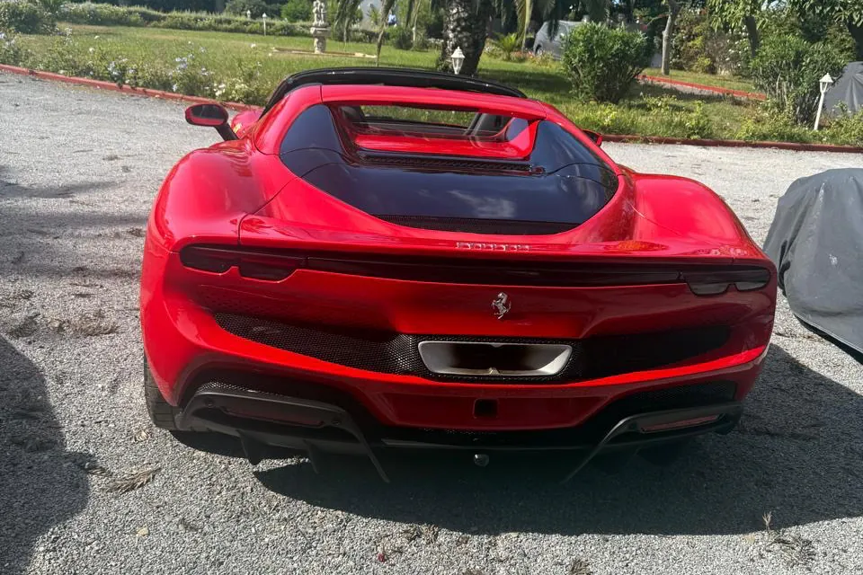 Rear view of the red Ferrari 296 GTS on a gravel driveway